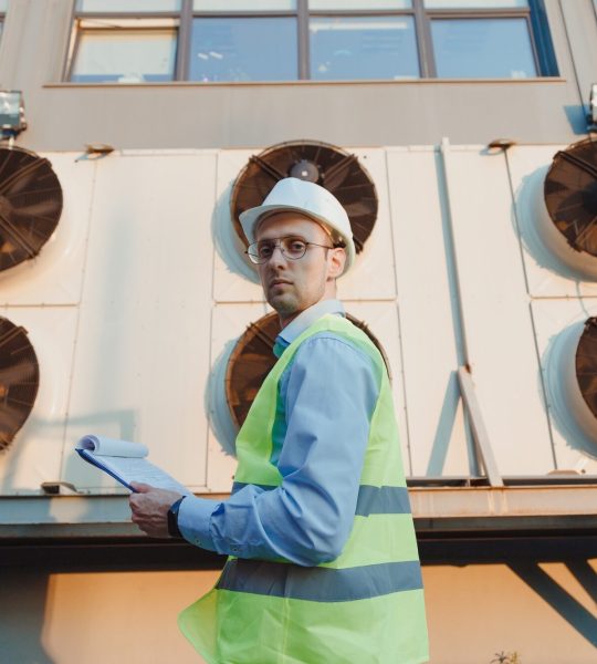 Service hvac engineer in uniform inspecting industrial refrigeration system